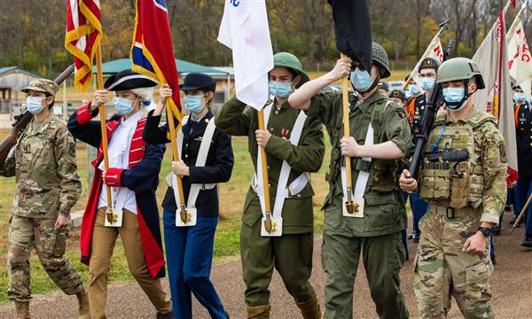 JROTC marches down road while carrying flags